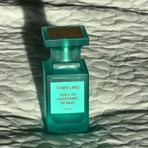 Säljer en elegant och fräsch parfym från Tom Ford, Sole di Positano Acqua, 50 ml. Flaskan är i en vacker turkos färg med en stilren design. Perfekt för sommardagar med sin lätta och uppfriskande doft. Kommer med en fyrkantig kork och guldiga detaljer. Passa på att köpa denna lyxiga doft! Ops jag har använt typ halva flaskan som ni ser på bilden ordinarie pris ligger på 1200 kr