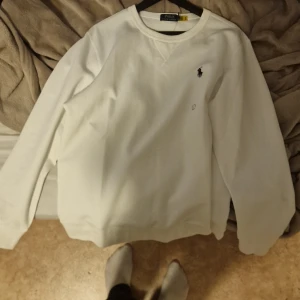 Vit tröja från Polo Ralph Lauren  - Säljer en snygg vit tröja från Polo Ralph Lauren i nytt skick. Den har en klassisk design med långärmade ärmar och det ikoniska Polo-logotypen broderad på bröstet. Perfekt för en stilren och avslappnad look. Passar till alla tillfällen! Prisen kan diskuteras