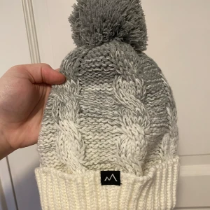 Grå och vit stickad mössa med tofs - Mössa, fint skick och använd 1,3 gånger MAX. KONTAKTA INNAN KÖP NU! 