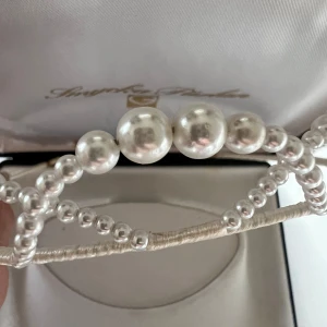 Elegant diadem med pärlor - Säljer ett supervackert diadem från Smycka Pärlan. Det är dekorerat med stora och små pärlor som ger en lyxig känsla. Perfekt för speciella tillfällen som bröllop eller fest. Diademet kommer i en fin förpackning och är i nytt skick.