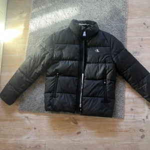 Svart pufferjacka från Calvin Klein Jeans - Säljer en fin svart pufferjacka från Calvin Klein Jeans i storlek S.                                                  Jackan har en dragkedja framtill och två praktiska fickor med dragkedjor.Jackan passar lika bra på kille som tjej💗Jackan är endast använd ett fåtal gånger så är i ett väldigt fint skick.