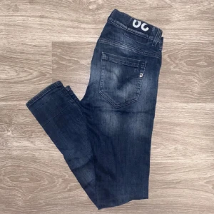 Mörkblå jeans med slitningar - Säljer nu dessa feta dondupjeans då jag inte använder de längre. De är jättebra skick och har inga fel. Tveka inte att höra av dig vid funderingar!