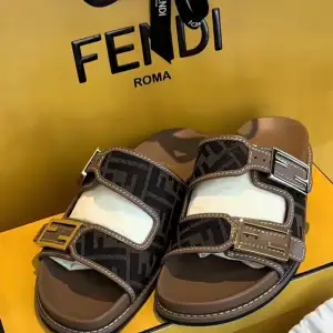 Snygga bruna sandaler från Fendi med två breda remmar och guldfärgade spännen. Remmarna har ett stilrent mönster med Fendi-loggan. Perfekta för sommaren och ger en lyxig touch till din outfit. Nypris 10200kr, köpta I Fendi butiken i Puerto Banus 2024 i somras. Kvitto, box och dustbags medföljer.