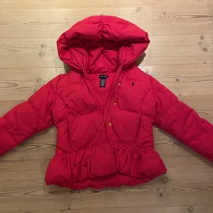 ROSA RALPH LOUREN JACKA - Säljer denna jättesnygga Ralph Lauren jacka. Storlek 12/14år. Något liten. Väldigt bra skick förutom att hanken lite sliten. Är jätteskön och varm och har en stor luva. 