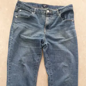 Säljer ett par klassiska blå jeans från Rosebud i storlek 46. De har en normal passform och är tillverkade i slitstarkt denim. Perfekta för vardagsbruk med en tidlös stil. Jeansen har knapp och dragkedja framtill samt fem fickor.