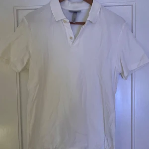 Vit kortärmad pikétröja - Säljer en klassisk vit pikétröja i bomull. Den har korta ärmar och en stilren krage med knappar. Perfekt för sommardagar eller en avslappnad stil. Passar både till vardags och lite finare tillfällen.