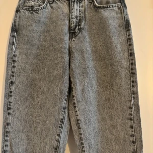 Grå jeans från Gina Tricot - Säljer ett par snygga grå jeans från Gina Tricot i storlek 36. De är tillverkade av hållbar bomull och har en klassisk design med fyra fickor och knappgylf. Perfekta för både vardag och fest! 🖤De är frabrikslitna vid midjan och längst ner (se de två sista bilderna) men byxorna är köpta så samt ska se ut så. 