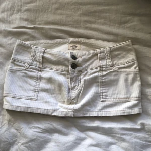 Vit kortkjol från Abercrombie & Fitch - Säljer en superfin vit kortkjol från Abercrombie & Fitch i 100% bomull. Perfekt för sommardagar eller en utekväll. Kjolen har en klassisk design med två knappar fram och är i mycket bra skick. Passar perfekt med en skinnjacka och stövlar för en chic look! 🖤