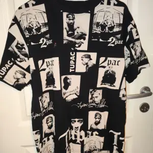 Cool svart T-shirt med massor av Tupac-tryck i vitt. Perfekt för dig som älskar hiphop och vill ha en unik stil. T-shirten är kortärmad och har en normal passform.