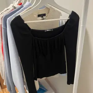 Snygg svart offshoulder-topp från Gina Tricot i ribbat material. Perfekt för en utekväll eller fest! Den har långa ärmar och en tight passform som framhäver figuren. En stilren och mångsidig topp som passar till både jeans och kjol.