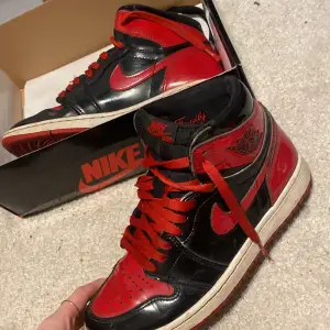 Säljer ett par Nike Air Jordan 1 Retro High OG Patent i svart och rött. Skorna är i bra skick och kommer med originalkartong och äktahetsbevis . De har en snygg glansig finish och klassisk snörning komme även med en extra svart snörning. Perfekta för både samlare och sneakerheads! Köpa för lite mer än 2000