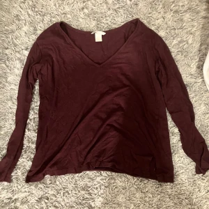 Vinröd långärmad tröja från H&M - Säljer en vinröd långärmad tröja från H&M i storlek XS. Tröjan har en v-ringad hals och är perfekt för både höst och vinter. Den är i bra skick och supermjuk, perfekt för mysiga dagar. Passar till både jeans och kjol! Verkligen en perfekt mysig höst tröja! Kan alltid gå ner i pris.