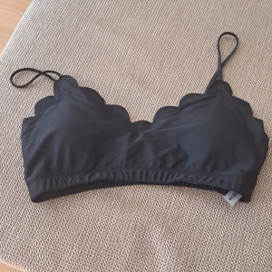 Svart bikiniöverdel med volangdetaljer - Säljer en snygg svart bikiniöverdel med volangdetaljer. Den har smala axelband och en bekväm passform. Perfekt för sommarens alla badäventyr!