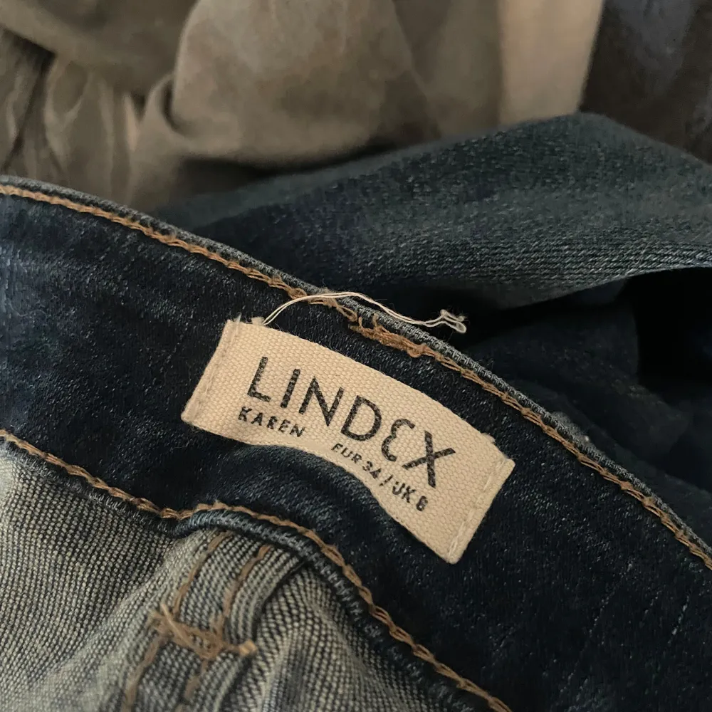 Säljer ett par snygga blå jeans från Lindex. De är i en klassisk blå färg och har en bootcut-stil som ger en skön retrovibe. Jeansen är högmidjade och sitter riktigt bra på. Perfekta för både vardag och fest!. Jeans & Byxor.