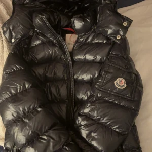 !Moncler jacka! -  Säljer denna stilrena moncler jackan i storlek 12y men passar 13y. Jackan är i fint skick. På sista bilden ser man att där man hänger upp är den är den sönder. Det finns et litet märke som man ser på näst sista bilden annars helt perfekt till vinter