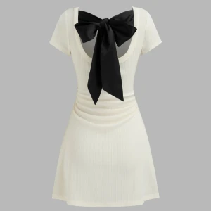 Vit ribbad klänning med svart rosett - Säljer en superfin vit ribbad klänning med en stor svart rosett i ryggen. Klänningen är kort (ungefär halvvägs ner till knäna på mig som är 178) och har en öppen rygg 🫶