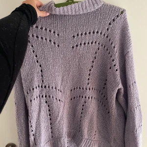 Ljuslila stickad tröja - Säljer en superfin ljuslila stickad tröja med ett snyggt hålmönster. Tröjan har en hög krage och långa ärmar, perfekt för kyliga dagar. Den är både mysig och stilren, idealisk för höst och vinter.