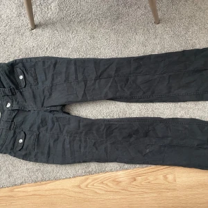 Lågmidjade jeans med detaljer - Lågmidjade svarta bootcut jeans med detaljer där fram. Säljer då de är lite små för mig.