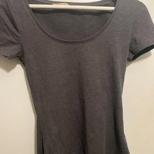 Grå tajt t-shirt från Anna Field - Säljer en stilren, grå och tajt t-shirt. Den har en enkel design med korta ärmar och rund halsringning. Knappt använd, så mycket bra skick. Skriv för fler bilder😌