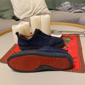 Mörkblå sneakers med röd sula(christian louboutins) - Snygga mörkblå sneakers med snörning och en kontrasterande röd sula. Perfekta för en stilren look med en twist. Skorna har en klassisk design med en modern touch. Säljer billigt pga skicket. Jag har box  (inget kvitto tyvärr). Tar även byten mot andra feta skor!🙏