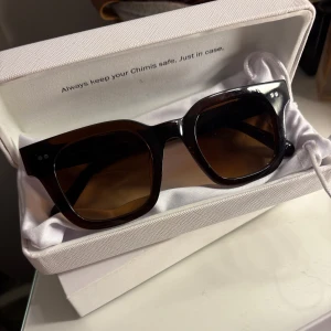 Mörkbruna solglasögon från Chimi - Snygga mörkbruna solglasögon från Chimi med fyrkantig form och bruna linser. Kommer med originalförpackning, fodral och putsduk. Använda fåtal gånger, som nya!