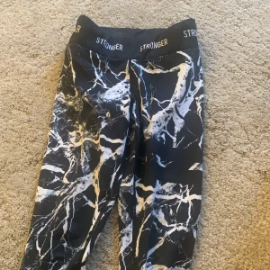 Mönstrade leggings från Stronger - Säljer ett par snygga leggings från Stronger i storlek S/xs . De har ett coolt mönster i svart, vitt och beige som påminner om marmor. Perfekta för träning eller en avslappnad dag. De är i mycket bra skick och har en bekväm passform med hög midja.