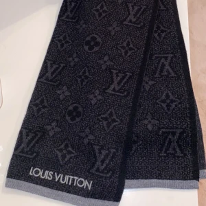 Svart och grå halsduk från Louis Vuitton - Säljer en elegant svart och grå halsduk från Louis Vuitton med det klassiska monogrammönstret. Perfekt för att hålla sig varm och stilren under kalla dagar. Passar både höst och vinter. 🖤köpt för 4 950kr använd 2 gånger.