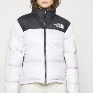 Vit och svart pufferjacka från The North Face - Säljer en snygg och varm pufferjacka från The North Face i vitt och svart. Jackan har en dragkedja framtill och är perfekt för kalla vinterdagar. Den är i mycket bra skick och passar både till vardags och utomhusaktiviteter. Köpt för 3745.