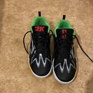 Svart gröna 2k scoot henderson basket skor från puma  - Snygga svarta sneakers från Puma med gröna och gula detaljer. Skorna har en unik design med silverfärgade mönster och en färgglad sula. Perfekt traction samt inte tunga. De är jävligt bekväma 