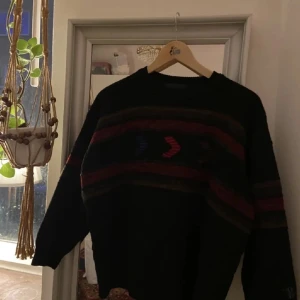 Mörk tröja med mönster - Säljer en mörk tröja med diskreta mönster i olika färger. Perfekt för kyliga dagar och ger en mysig känsla. Tröjan har långa ärmar och en klassisk passform. Passar bra till både vardag och avslappnade tillfällen.