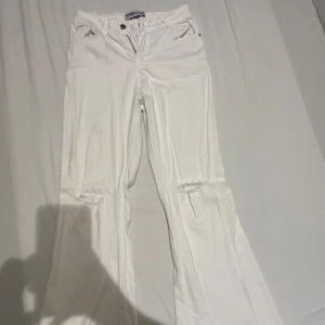 Vita jeansbyxor från YMR - Säljer ett par vita jeansbyxor från YMR med slitna detaljer vid knäna. Byxorna har en knapp och dragkedja framtill samt fem fickor. Perfekta för en stilren look. Dem är köpa utomlands och är väldigt sköna & stretchiga!! Passar storlek M-L