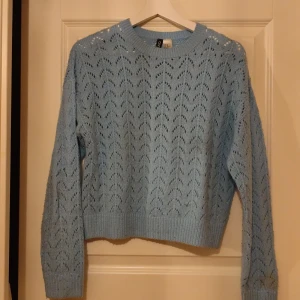 Ljusblå stickad tröja från Divided - Säljer en ljusblå stickad tröja från Divided med ett snyggt hålmönster. Tröjan har långa ärmar och ribbade kanter vid hals, ärmslut och nederkant. Perfekt för kyliga dagar! 💙