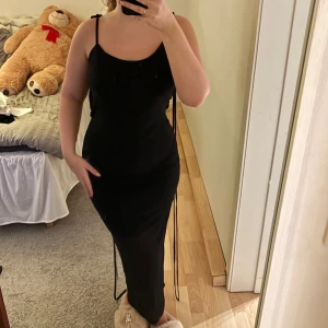 Svart glittrig klänning - Snygg svart klänning med glittrigt material och smala axelband som man själv kan knyta. Den har en tight passform och en elegant öppen rygg. Perfekt för en kväll ute! Super snygg😍