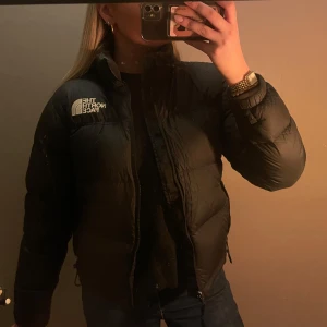 The north face retro nuptse jacka - Säljer en svart dunjacka från The North Face. Jackan har en hög krage och dragkedja framtill. Jackan är i jätte fint skick och inga defekter.      Nytt pris 3499kr