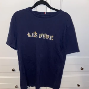 Mörkblå t-shirt från Les Deux - Snygg mörkblå t-shirt från Les Deux med tryck på bröstet. Perfekt för en avslappnad stil. Tillverkad i mjukt material för extra komfort.