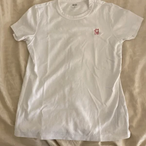 Vit t-shirt med röd kattbroderi från Uniqlo - Säljer en vit t-shirt från Uniqlo i storlek M. Den har ett litet rött broderi av en katt på bröstet. Perfekt för en avslappnad stil och passar till alla tillfällen. T-shirten är i bomull och har en normal passform. Skicka ett meddelande vid intresse!