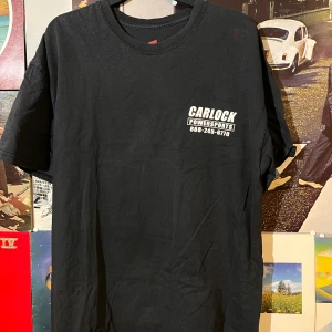 Svart t-shirt från Hanes med Carlock Powersports-tryck - Säljer en svart t-shirt från Hanes. T-shirten har ett tryck med texten 'Carlock Powersports' och ett stort motiv på baksidan. Finns tyvärr en röd fläck på vänster ärm annars bra cond