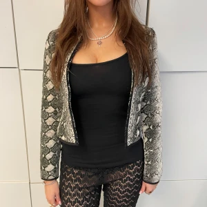 KOFTA MED ORMSKINNSMÖNSTER - Kofta med ormskinmsmönster! Perfekt till både vardag och fest beroende på hur man stylar! Koftan går även att knäppa med hängen som inte syns, så nice. Modellen är 175 cm och koftan är S. Hör av er vid frågor! P.S kolla vår plick för byxorna i bilden😉