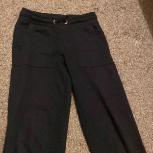 Svarta mjukisbyxor - Säljer ett par svarta mjukisbyxor i storlek 140. De har en elastisk midja med snörning och praktiska fickor fram och bak. Perfekta för en avslappnad dag hemma eller för träning. Byxorna är i bra skick och superbekväma!