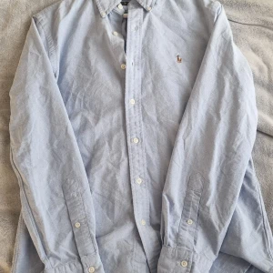 Ljusblå skjorta från Ralph Lauren - Säljer en klassisk ljusblå långärmad skjorta från Ralph Lauren i storlek S. Skjortan är endast använd vid ett tillfälle och är tillverkad i 100% bomull.