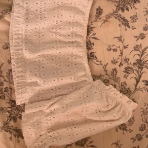 Vit kjol med spetsdetaljer - Superfin vit kjol med spetsdetaljer, perfekt för sommardagar eller midsommarfirande. Kjolen har en luftig passform och är gjord i ett lätt material som känns skönt mot huden. Den har ett elastiskt band i midjan för extra komfort. Passar perfekt till en enkel topp eller blus för en söt och stilren look.