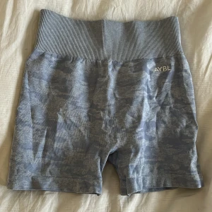 Grå shorts från AYBL - Säljer ett par grå shorts från AYBL med hög midja och ett diskret mönster. Perfekta för träning med en bekväm passform och elastiskt material. 