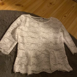 Vit spetsblus i storlek XS - Säljer en superfin vit spetsblus i storlek XS. Blusen har trekvartsärmar och ett vackert spetsmönster som ger en romantisk känsla. Perfekt för både vardag och festliga tillfällen. Passar bra till jeans eller kjol för en chic look! Använt bara en gång!