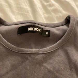 Superfin grå topp - Säljer en stilren grå ärmlös topp från BikBok i storlek M. Perfekt för en casual look eller att ha under en jacka. Toppen är i bra skick och har en enkel design som passar till det mesta.