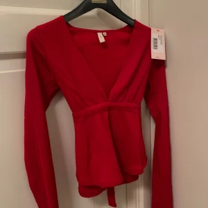 Röd omlottopp med knytband - Säljer en helt ny omlottopp från Nelly då den var för stor, pallar ej skicka tibx 🫤 perfekt till julen med en rosett på ryggen. Nypris är 199 kr och jag köpt den för 125 kr på black week ❤️