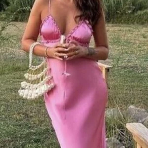Rosa sidenklänning - Rosa sidenklänning med smala axelband och djup urringning. Klänningen har knytning framtill och en öppen rygg. Inte mina bilder! Aldrig använd, prislapp kvar på 