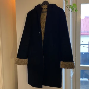 Svart kappa med foder - Säljer en snygg svart kappa med mysigt foder från NEXT. Mocca- och pälsimitation. Sparsamt använd, men dragkedjan kan kärva till och från, men går alltid att fixa.  EUR 40, men är mer strl 38/S