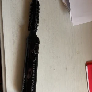 Braun stylingverktyg - Bild på en svart hårstyler med borsthuvud, perfekt för att skapa volym och lockar. Den har en sladd och en knapp för att justera värmen. Perfekt för att fixa håret snabbt och enkelt hemma. Testad en gång bara