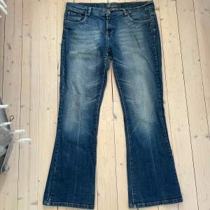 Säljer ett par snygga blå bootcut jeans. De har en fin tvättad look och broderade detaljer på bakfickorna. Midjemått: 48cm Innerbenslängd: 73cm Skriv om du undrar något! Skulle tippa storleken runt S/M