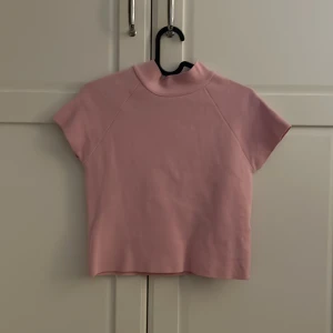 Rosa kortärmad topp - Säljer en söt rosa kortärmad topp med hög krage. Perfekt för både vardag och festliga tillfällen. Toppen har även  mjukt material! 